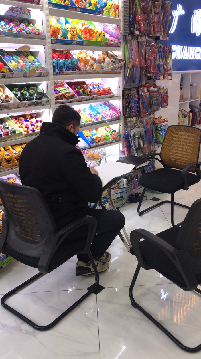 An overseas client taking notes at a supplier booth in a Chinese wholesale market